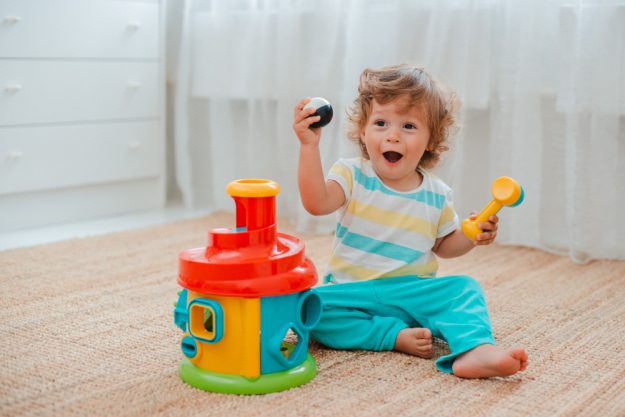 baby-plays-on-the-floor-in-the-room-in-educational-plastic-toys